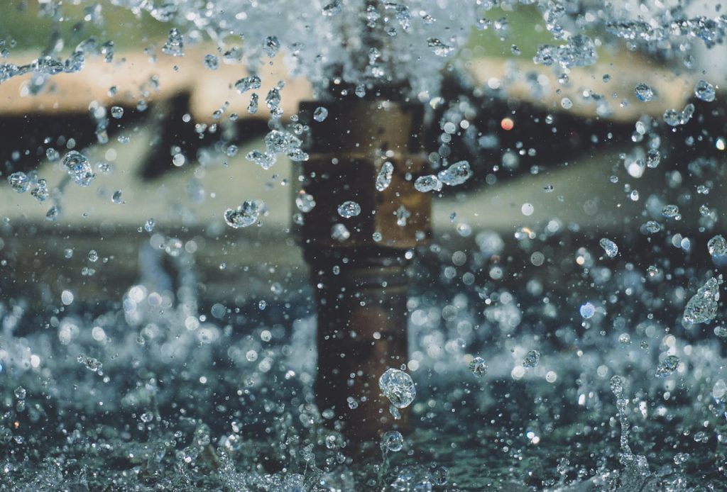 Close-up of water droplets mid-air from a fountain, capturing motion and clarity in an outdoor setting.